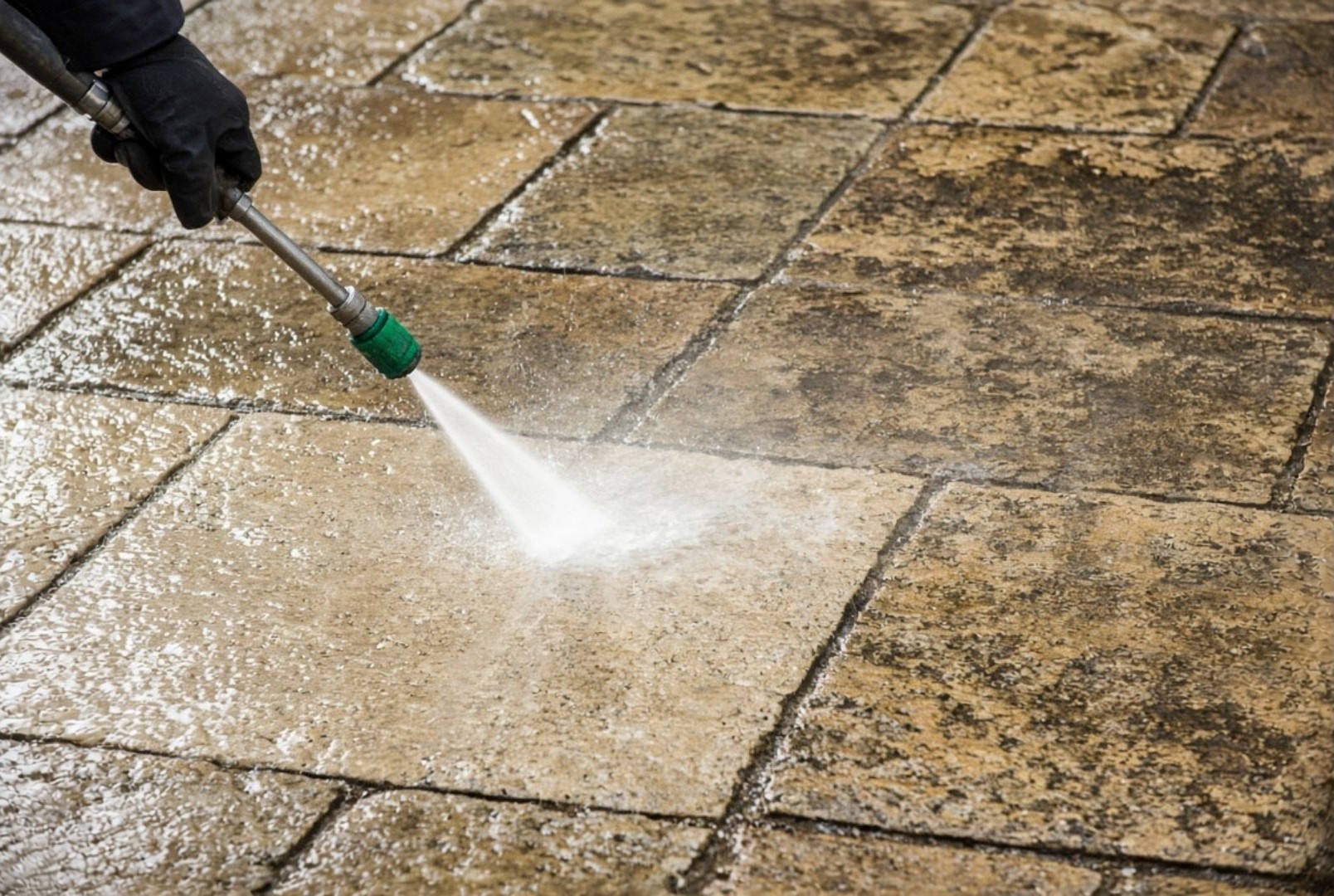 Pressure washing a stone patio with visible clean and dirty contrast